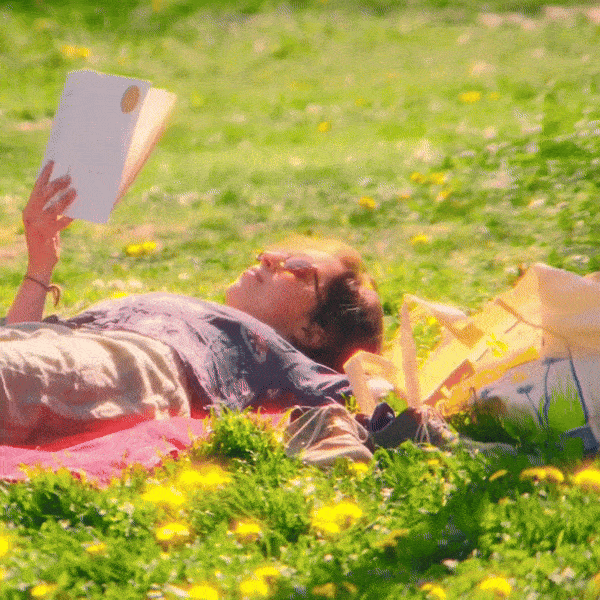 Someone reading a book in a lawn sprinkled with flowers